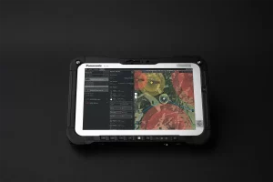 Close-up of a UAV Mission Planner showing map overlays and flight control settings on a rugged tablet